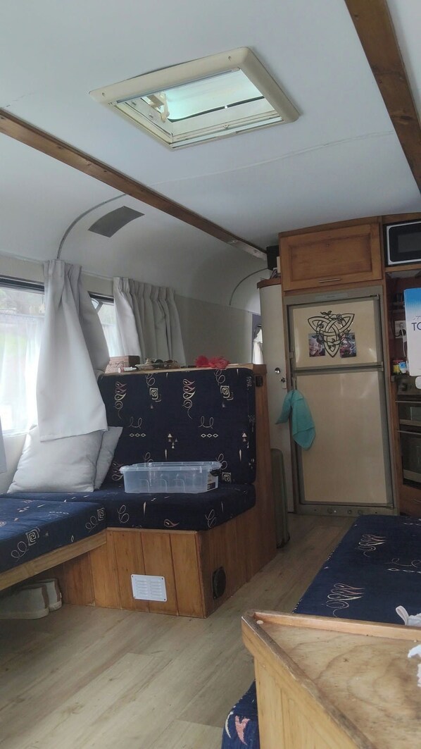 Un espace de vie compact comprenant un lit superposé, une kitchenette et un petit réfrigérateur.