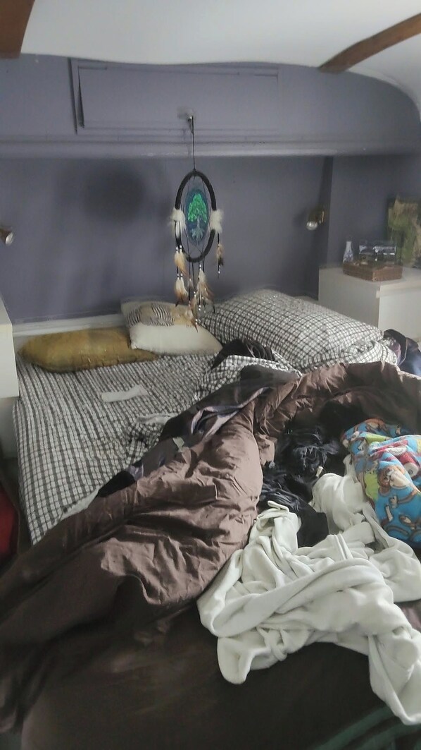 Une chambre à coucher avec un lit, des oreillers, un attrape-rêves et une commode.