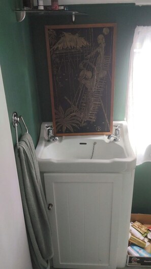 Une salle de bain avec un lavabo blanc, un porte-serviettes et un tableau encadré au-dessus du lavabo.