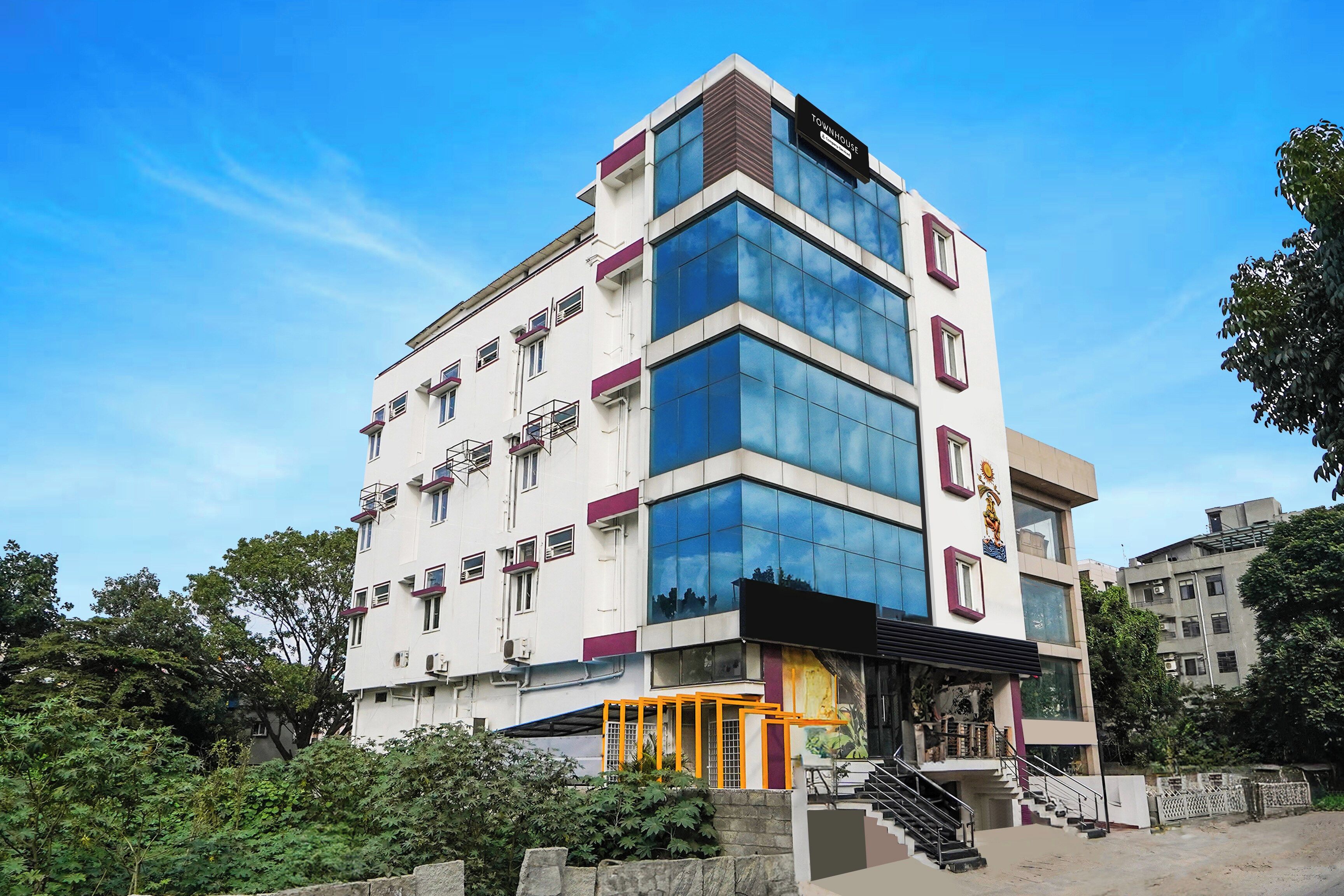 A multi-story building with a modern architectural design, featuring a mix of glass and concrete facades, and a prominent entrance with a staircase.
