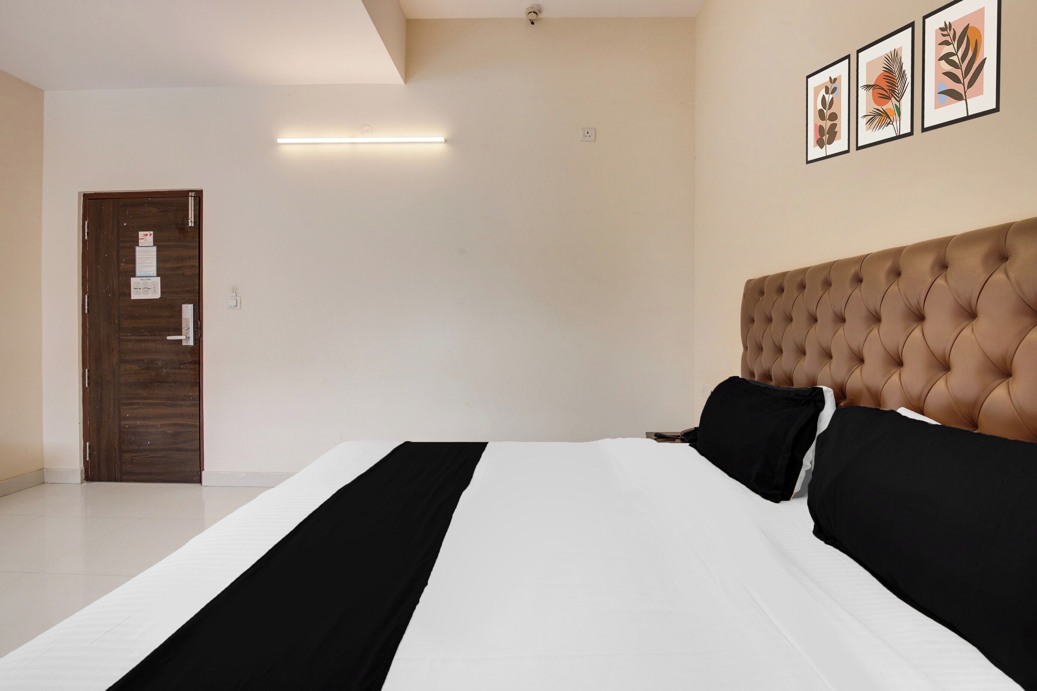 Un dormitorio con una cama, una puerta, una lámpara y cuadros en la pared.