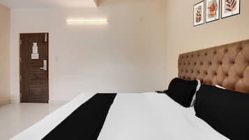 Un dormitorio con una cama, una puerta, una lámpara y cuadros en la pared.
