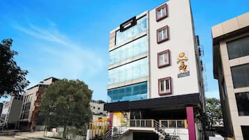 Un edificio de varios pisos con un diseño arquitectónico moderno, que destaca por una entrada con escaleras y fachada de vidrio.