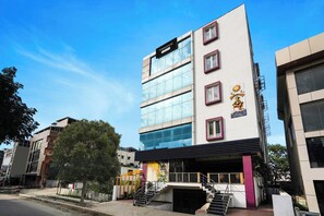 Un edificio de varios pisos con un diseño arquitectónico moderno, que destaca por una entrada con escaleras y fachada de vidrio.
