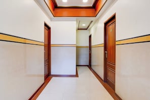 Un pasillo con puertas a ambos lados, piso de baldosas e iluminación empotrada en el techo.