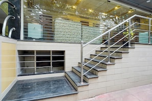 Una escalera con barandas de metal y una baranda de cristal en el descansillo superior.