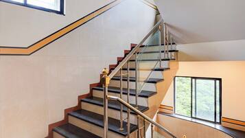 Een moderne trap met glazen leuning en een metalen handrail, die naar een verdieping leidt.