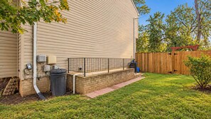 A residential exterior with a brick foundation, a metal fence, and a wooden deck. - Cozy Private Basement Unit Near DC & Metro (Glenarden)