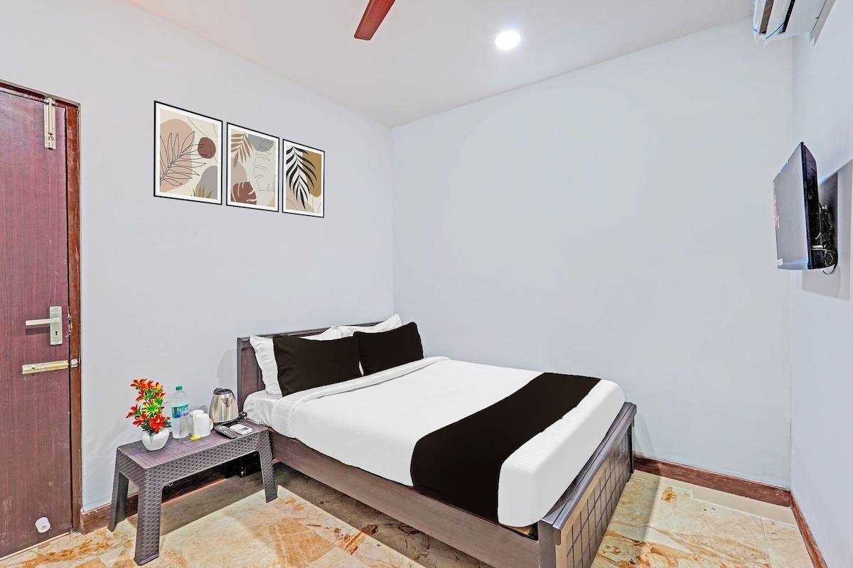 Una habitación de hotel con una cama, una mesita de noche, un televisor y una puerta.