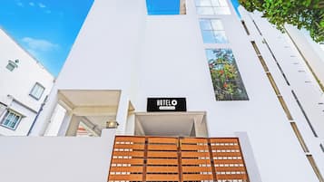 Een modern gebouw met een witte gevel, een houten poort en een bord waarop staat 'HOTELO Company-Serviced'.