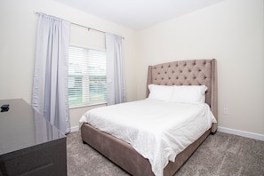 A bedroom with a bed, a bedside table, and a window with curtains. - NEW 5BR Private Pool Lazy River Resort 8955 (Davenport)