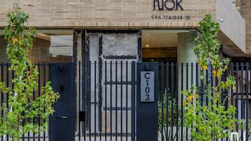 Una entrada de edificio con una reja negra, un cartel de dirección visible y un frente de ladrillo.