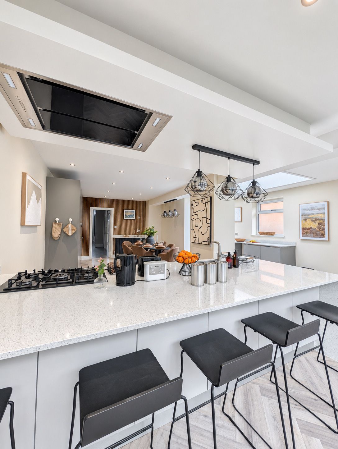 A modern kitchen with a central island, bar stools, and pendant lighting.
