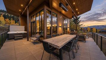Un patio moderno al aire libre con una mesa de comedor, sillas, una parrilla de barbacoa y un jacuzzi.