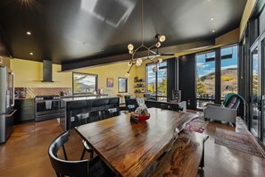 Cocina moderna con isla central, comedor con sillas y ventanas amplias con vistas al exterior.