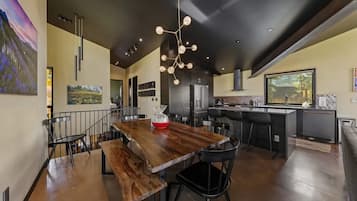 Una cocina moderna con una isla central, iluminación colgante y un comedor con mesa y sillas de madera.