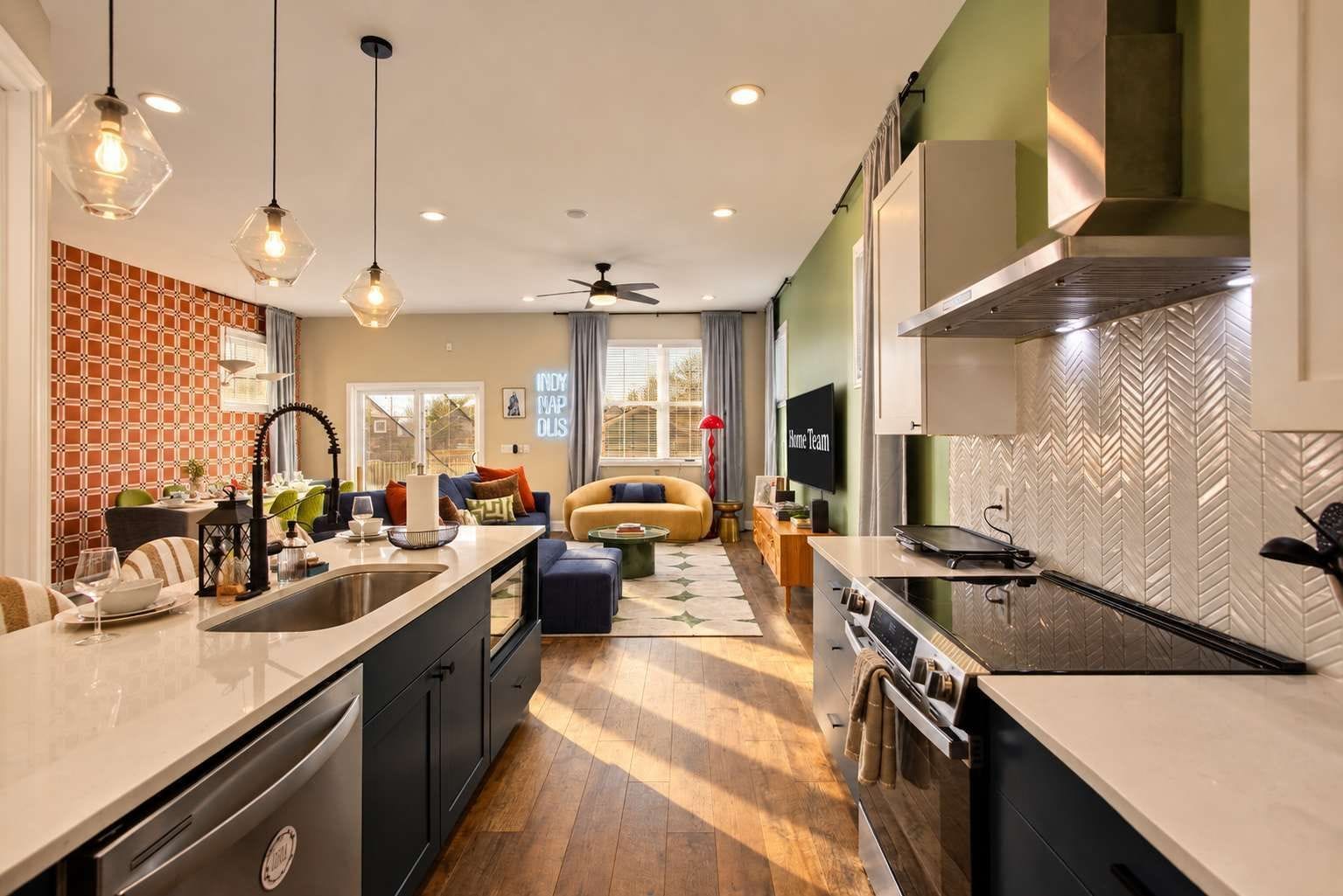 A modern kitchen with a central island, built-in oven, and a dining area with a sofa and table.
