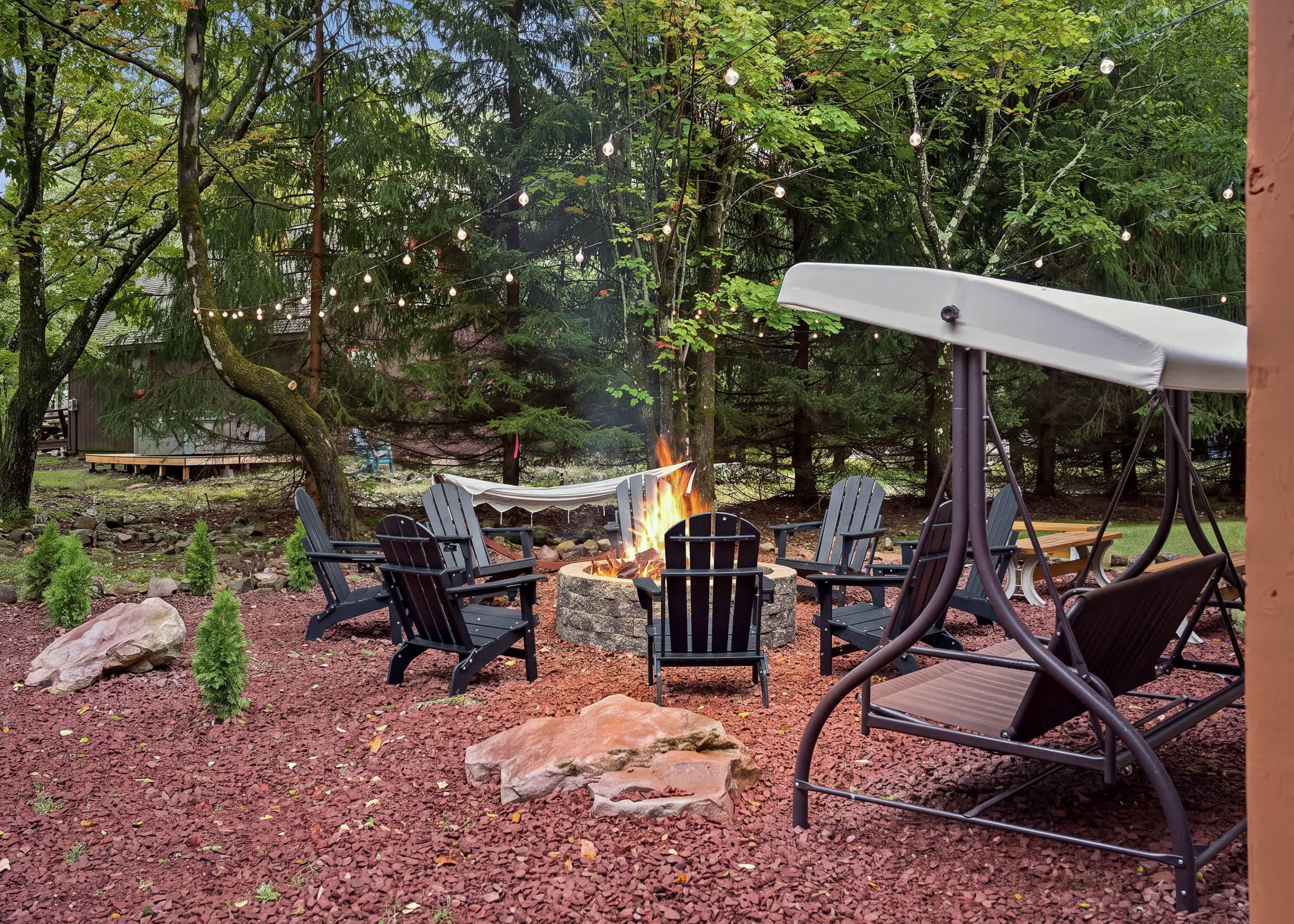 An outdoor seating area with Adirondack chairs, a swing chair, and a fire pit.