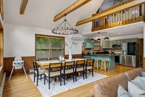 A spacious kitchen with modern appliances, a dining area with a wooden table and chairs, and a cozy living room with a brown sofa. - Poconos Retreat Sauna Hot Tub Fire Pit Games (Lake Harmony)