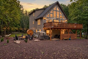 A two-story house with a deck, outdoor seating area, and a fire pit. - Poconos Retreat Sauna Hot Tub Fire Pit Games (Lake Harmony)