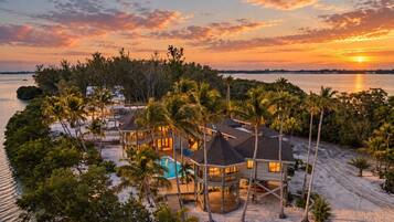 A beachfront property with a swimming pool, multiple buildings, and palm trees.