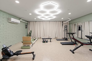 A gym with exercise equipment, a wall-mounted air conditioner, and a mirror. - Lakin It Easy Luxe Waterfront Oasis Sleeps 16 (Mesa)