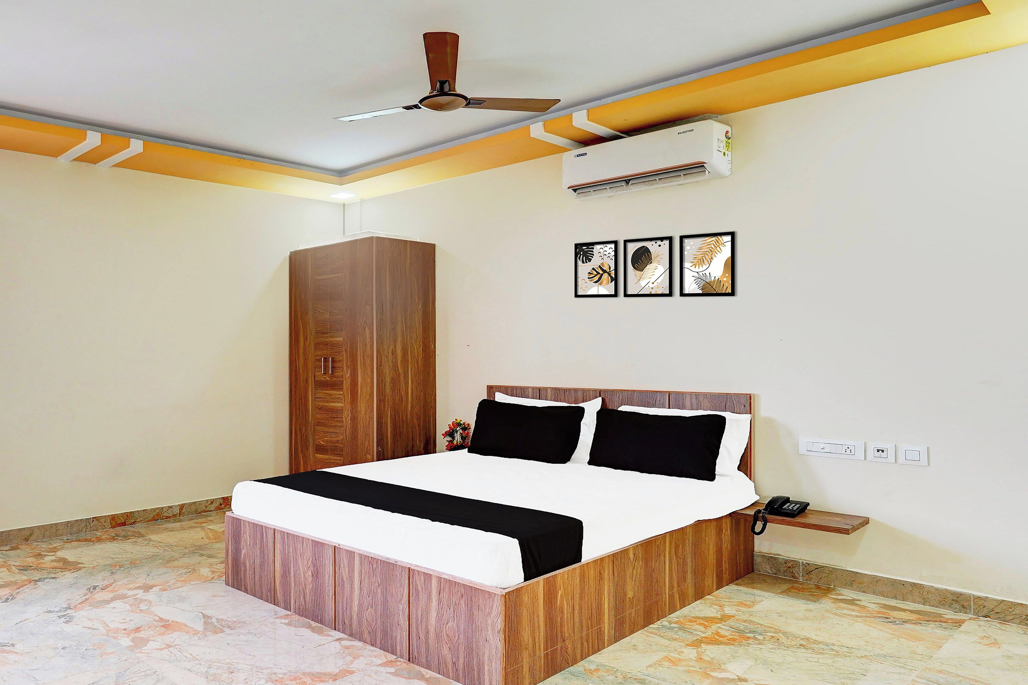 A bedroom with a bed, a wardrobe, a ceiling fan, an air conditioner, and a wall-mounted phone.