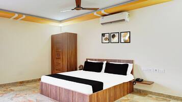 A bedroom with a bed, a wardrobe, a ceiling fan, an air conditioner, and a wall-mounted phone.