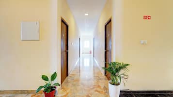 Un pasillo de hotel con piso de mármol, puertas de madera y plantas en macetas.