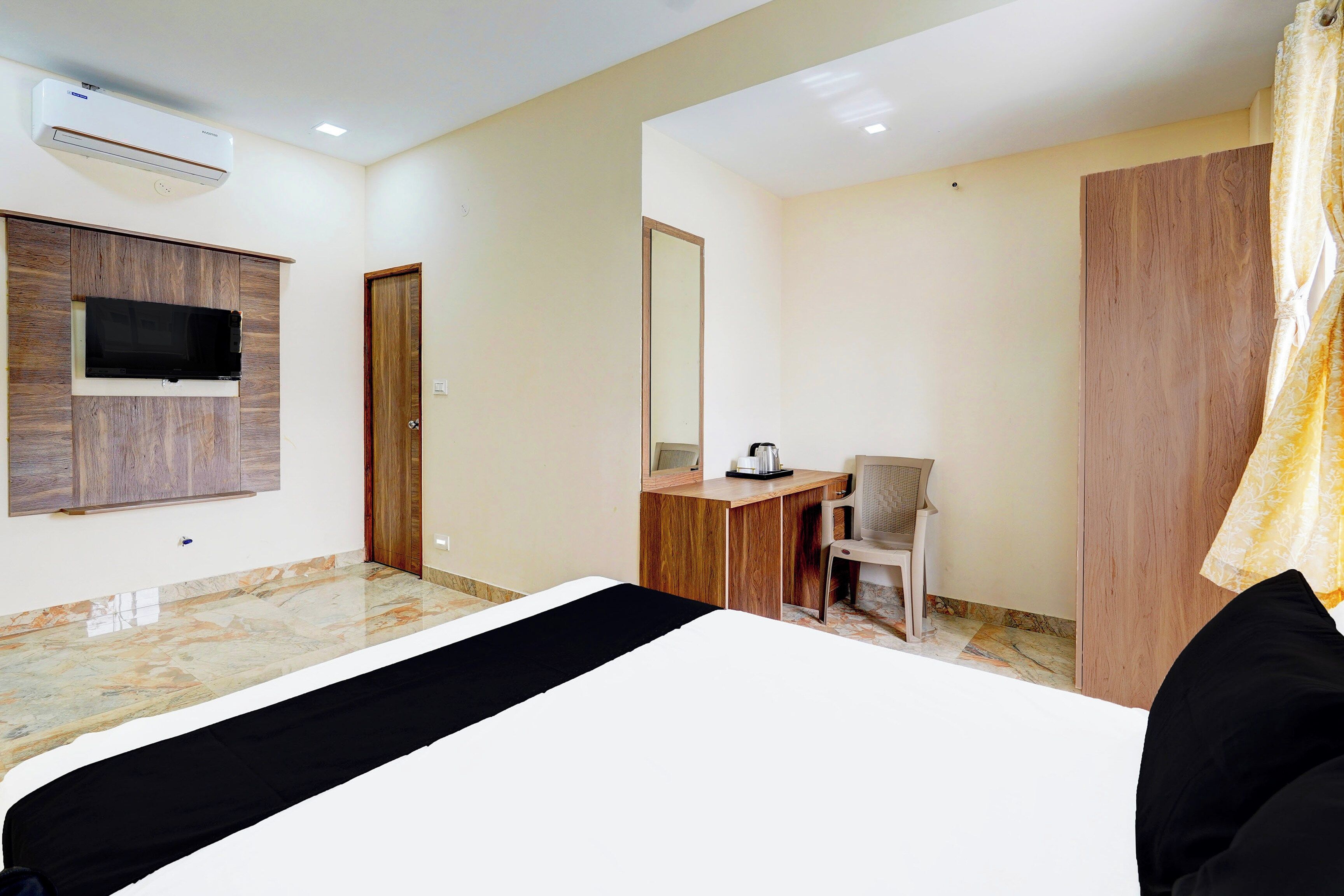 Una habitación de hotel con una cama, un escritorio, una silla, un televisor y un armario.