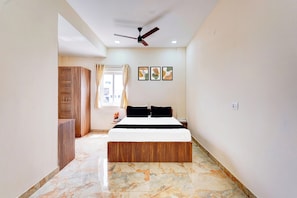 A bedroom with a bed, a ceiling fan, and a window with curtains.