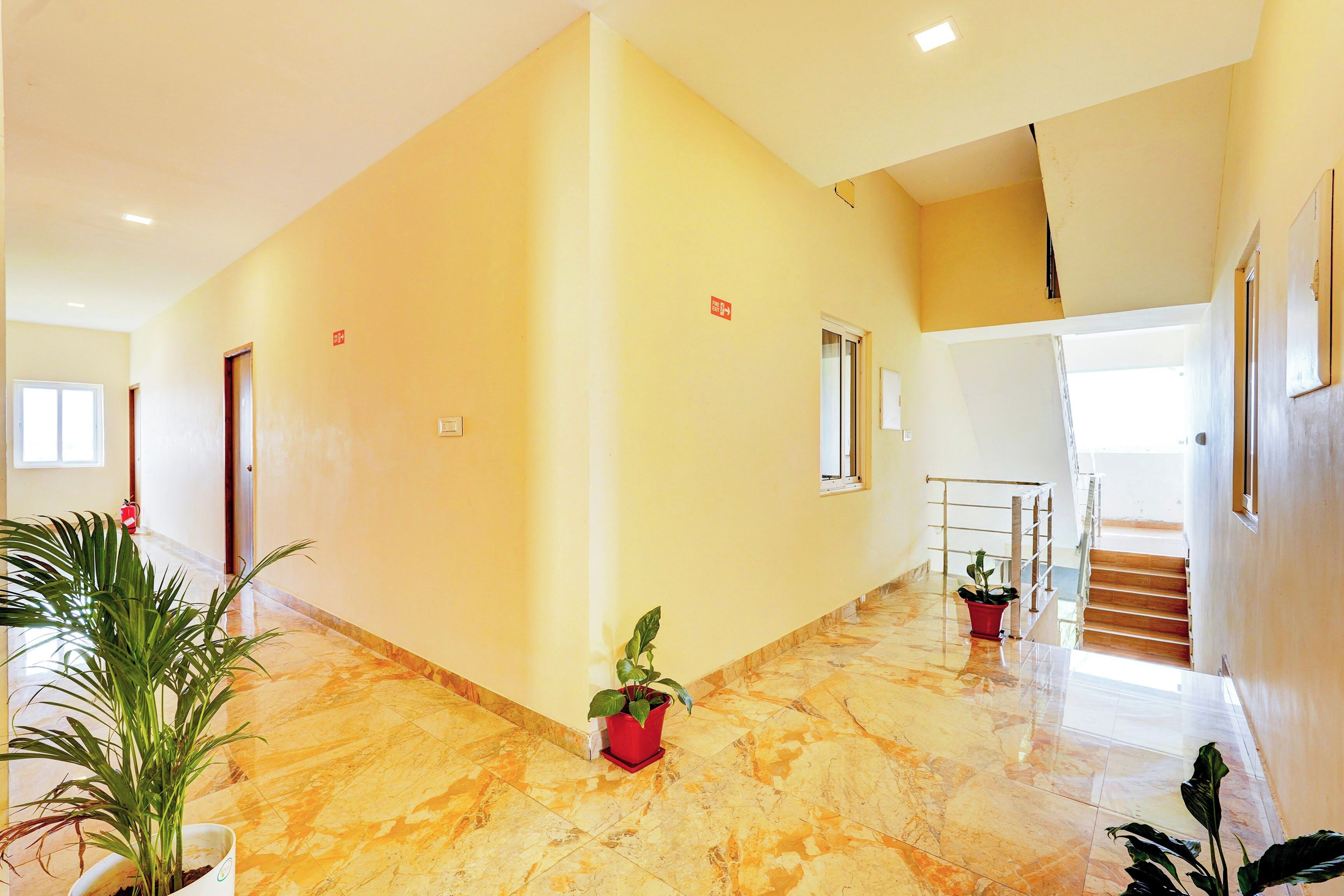 A spacious interior with a marble floor, a staircase, and potted plants.