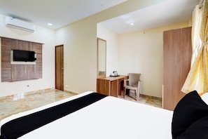 A hotel room with a bed, a desk with a chair, a television, a wardrobe, and an air conditioning unit. - Hotel O Sriperambadhur (Sriperumbudur)