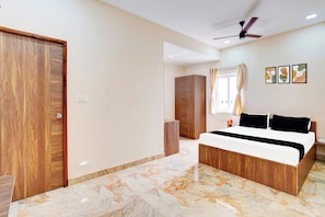 A bedroom with a bed, wooden wardrobe, marble flooring, ceiling fan, and artwork on the wall. - Hotel O Sriperambadhur (Sriperumbudur)
