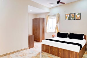 A bedroom with a bed, wooden wardrobe, a ceiling fan, and a window with curtains. - Hotel O Sriperambadhur (Sriperumbudur)