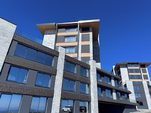 Un immeuble à plusieurs étages doté de grandes fenêtres et d’une façade combinant des éléments en pierre et en bois.