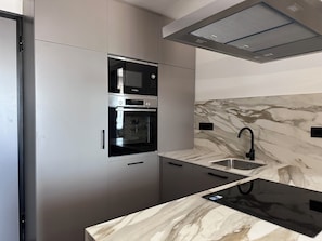 Une cuisine moderne dotée d’appareils électroménagers intégrés, d’un pare-feu en marbre et d’un robinet élégant.