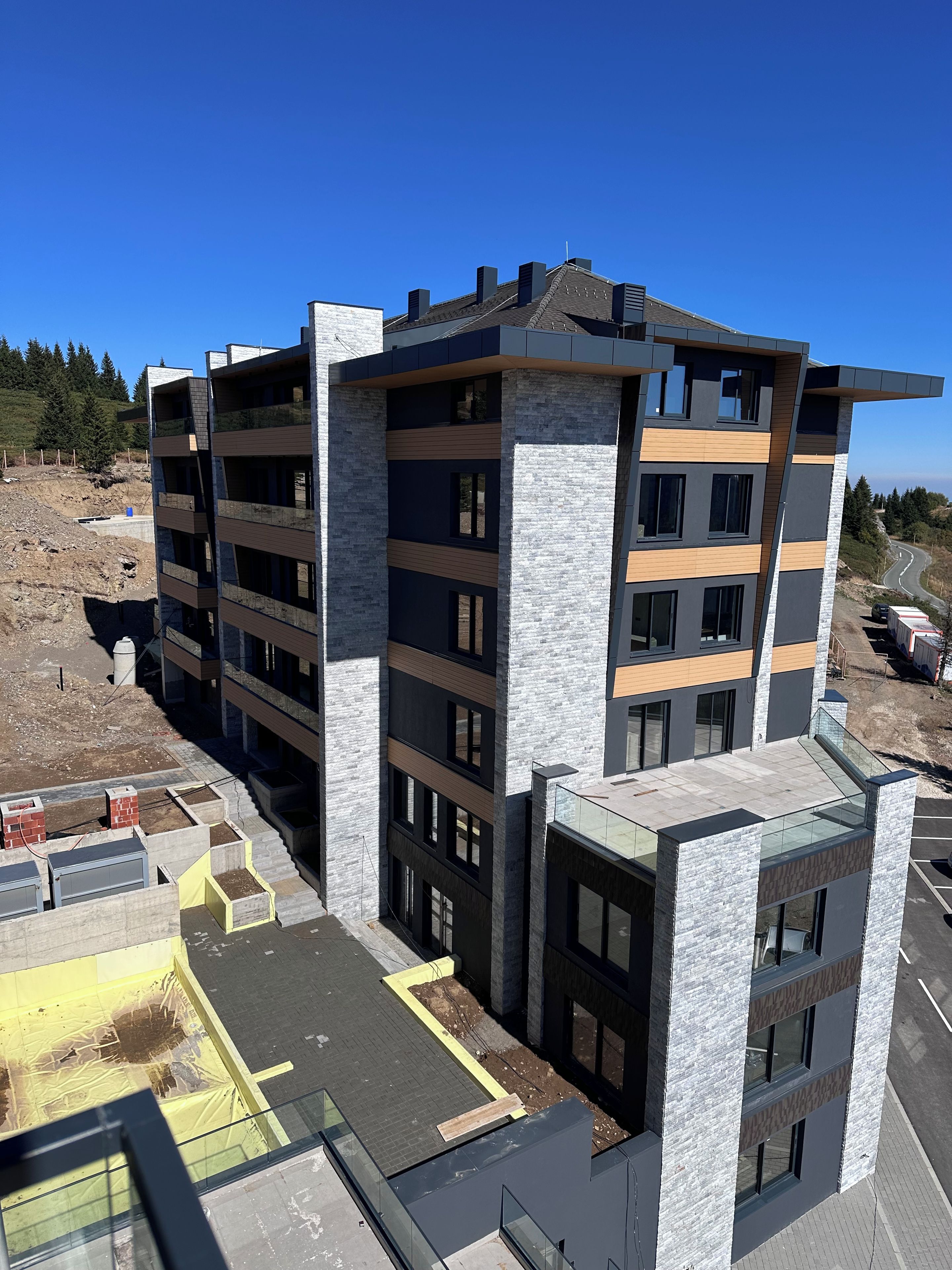 A multi-story building with a modern architectural design, featuring a combination of brick and stone facades, large windows, and a flat roof.