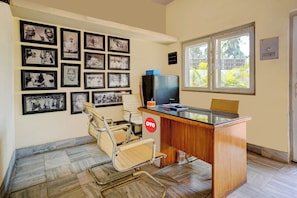 Una habitación con escritorio, televisor y una silla. Varias fotografías enmarcadas adornan la pared.