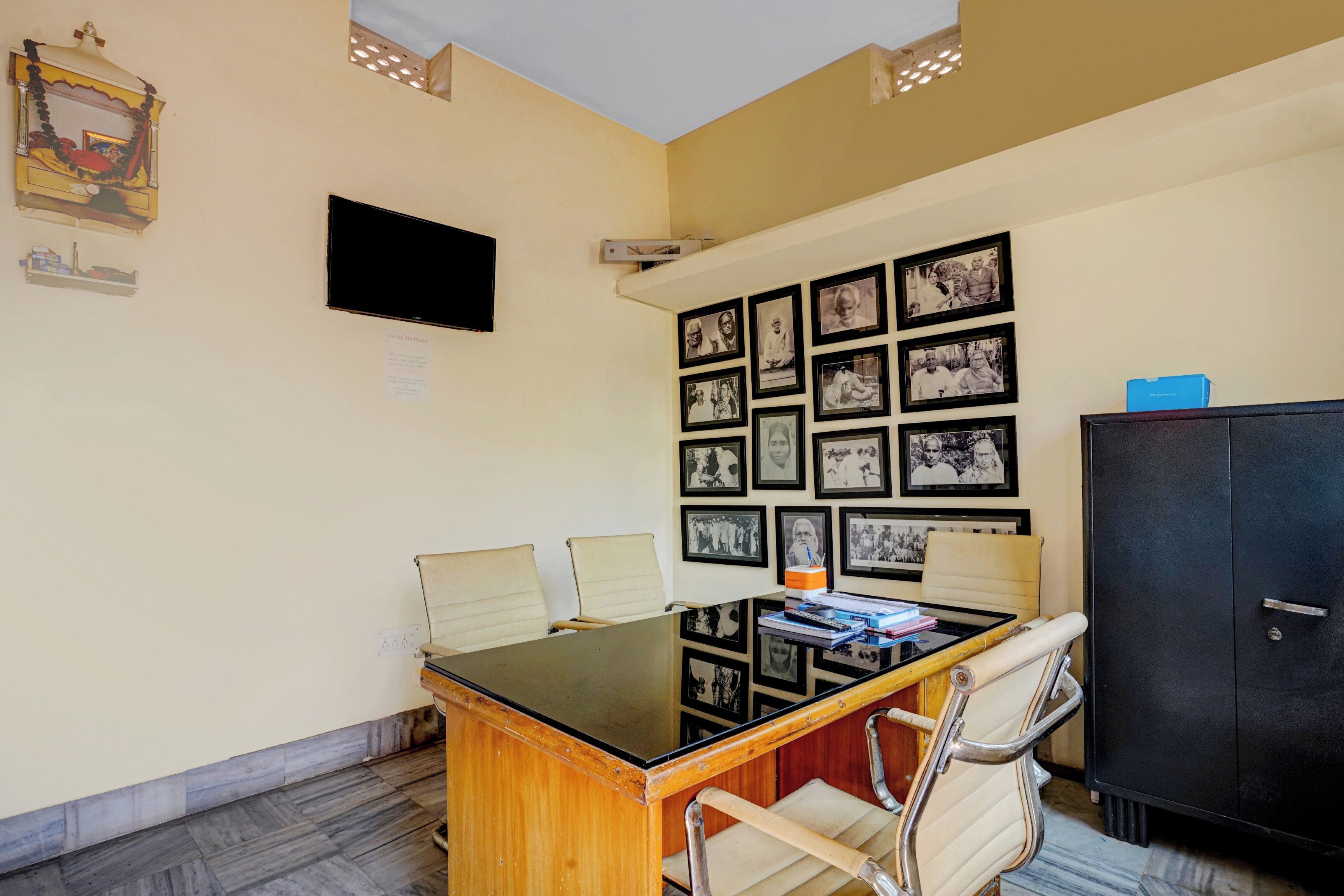 A conference room with a table, chairs, a TV, and a wall adorned with framed photographs.