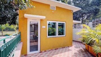 A yellow building with a door labeled 'OFFICE/ENQUIRY,' a window, and a tiled patio area with potted plants.