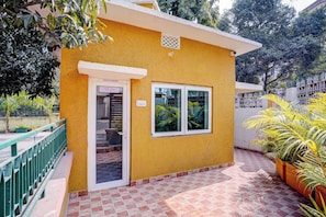 Un edificio amarillo con una puerta que indica 'OFFICE/ENQUIRY', una ventana y un patio con baldosas y plantas en macetas.