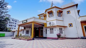 A building with a sign 'OYO' indicating a hotel. It has a covered entrance with a yellow and white color scheme.