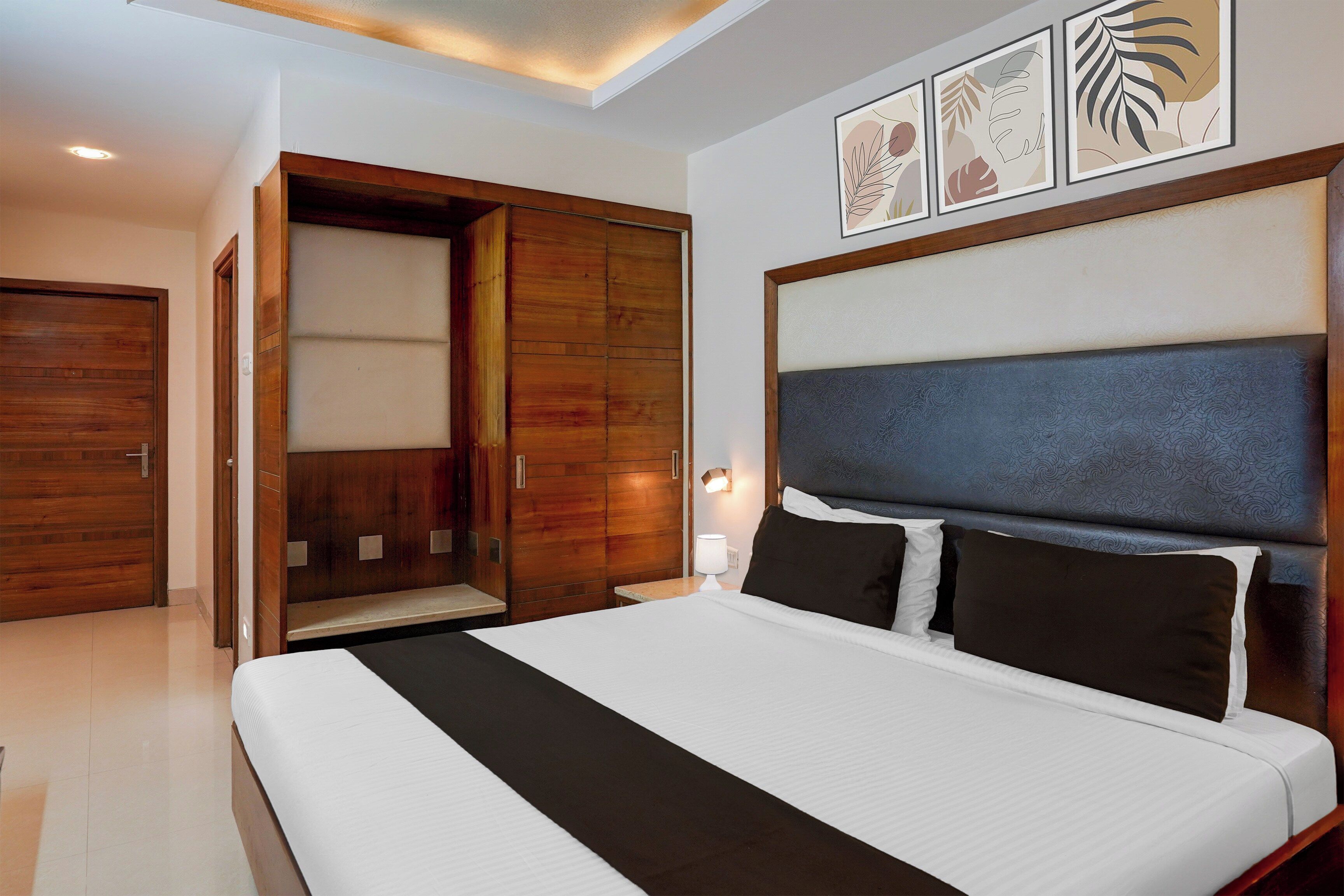 Una habitación de hotel con una cama, un armario y una mesita de noche con lámpara.
