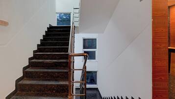 A staircase with a metal handrail leading to a door with a window.