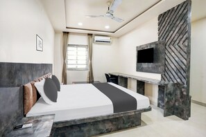 Una habitación de hotel moderna con cama, escritorio, televisor y aire acondicionado.