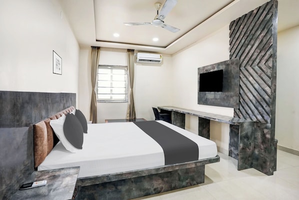 Una habitación de hotel moderna con cama, escritorio, televisor y aire acondicionado.