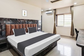Une chambre d’hôtel avec un lit, un bureau et une fenêtre avec des rideaux.