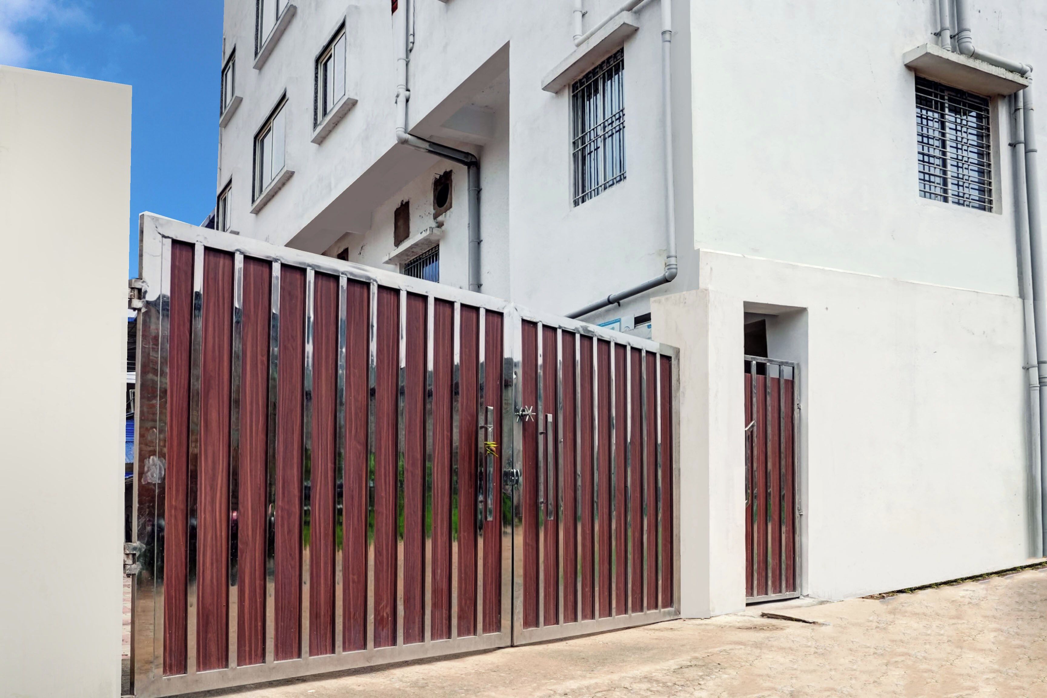 Una entrada protegida por un portón a un edificio con fachada blanca y varias ventanas.