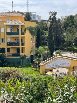 Un edificio amarillo con un letrero que dice 'Mijar Golf House' y una entrada protegida por una reja.